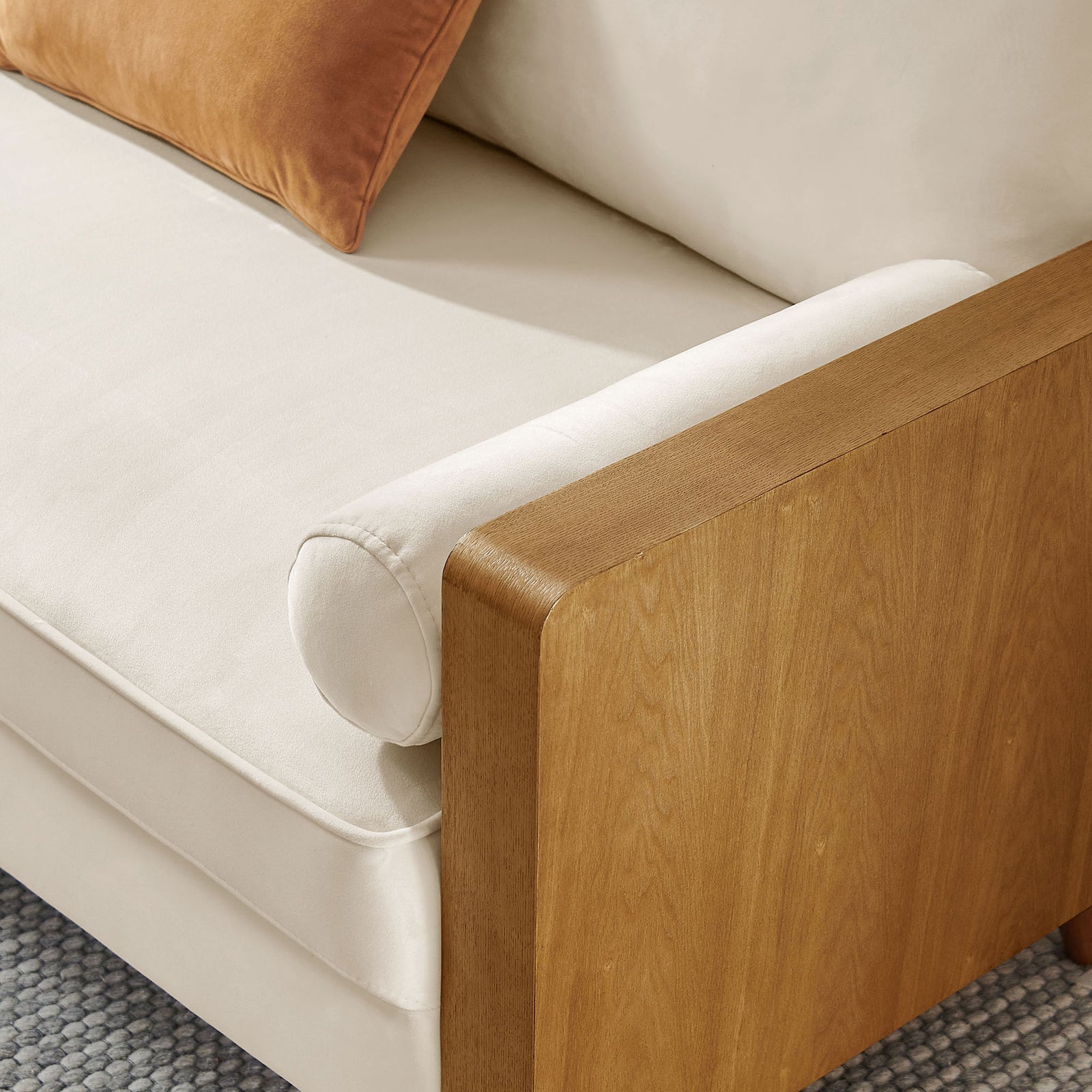 Cozy corner detail with cream velvet cushions, bolster pillow, and walnut armrest styled with a soft rug || EEI-6945-WAL-ALA || detail_room