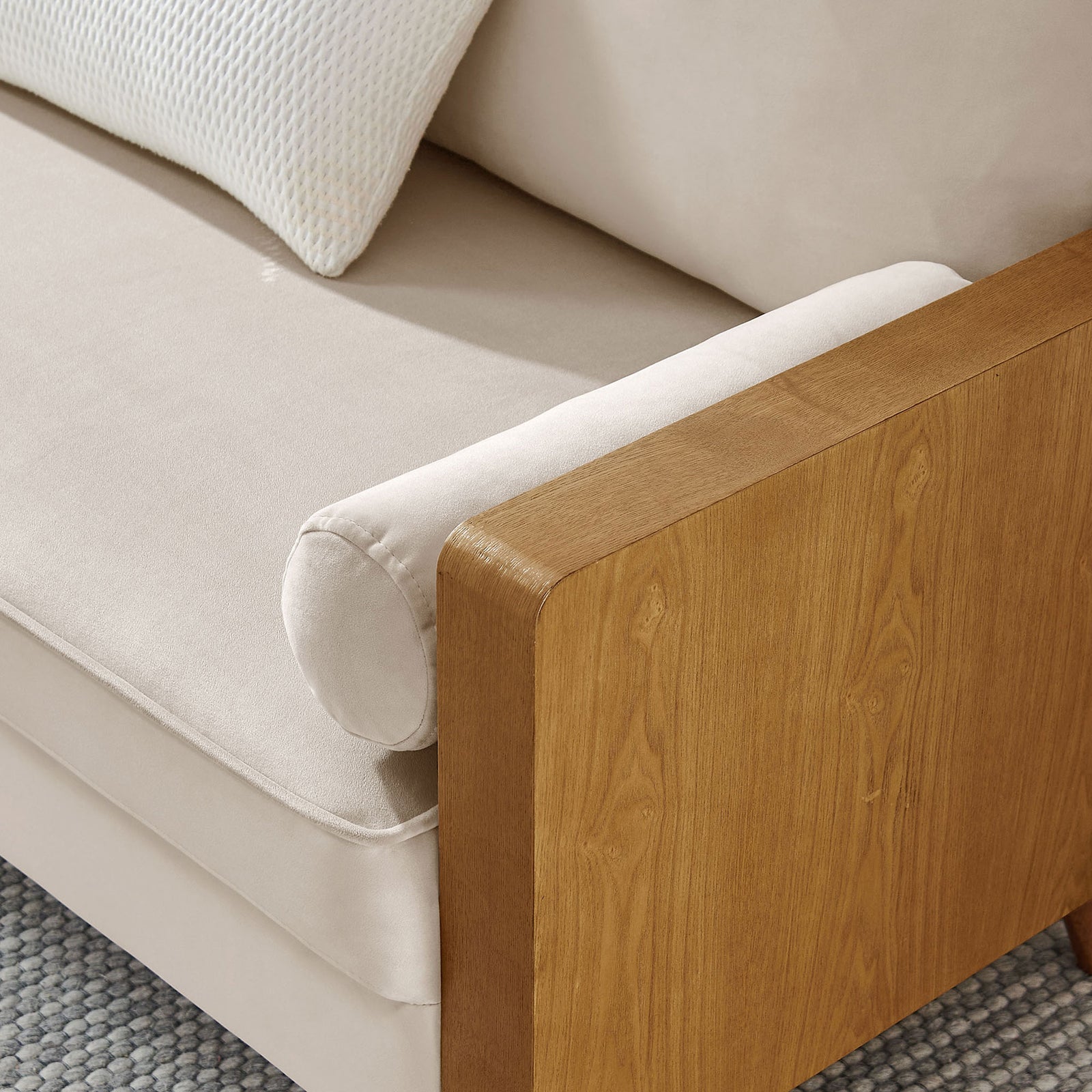 Velvet bolster pillow resting against wood arm and seat cushion in a cozy setting || EEI-6945-WAL-ALM || detail_room