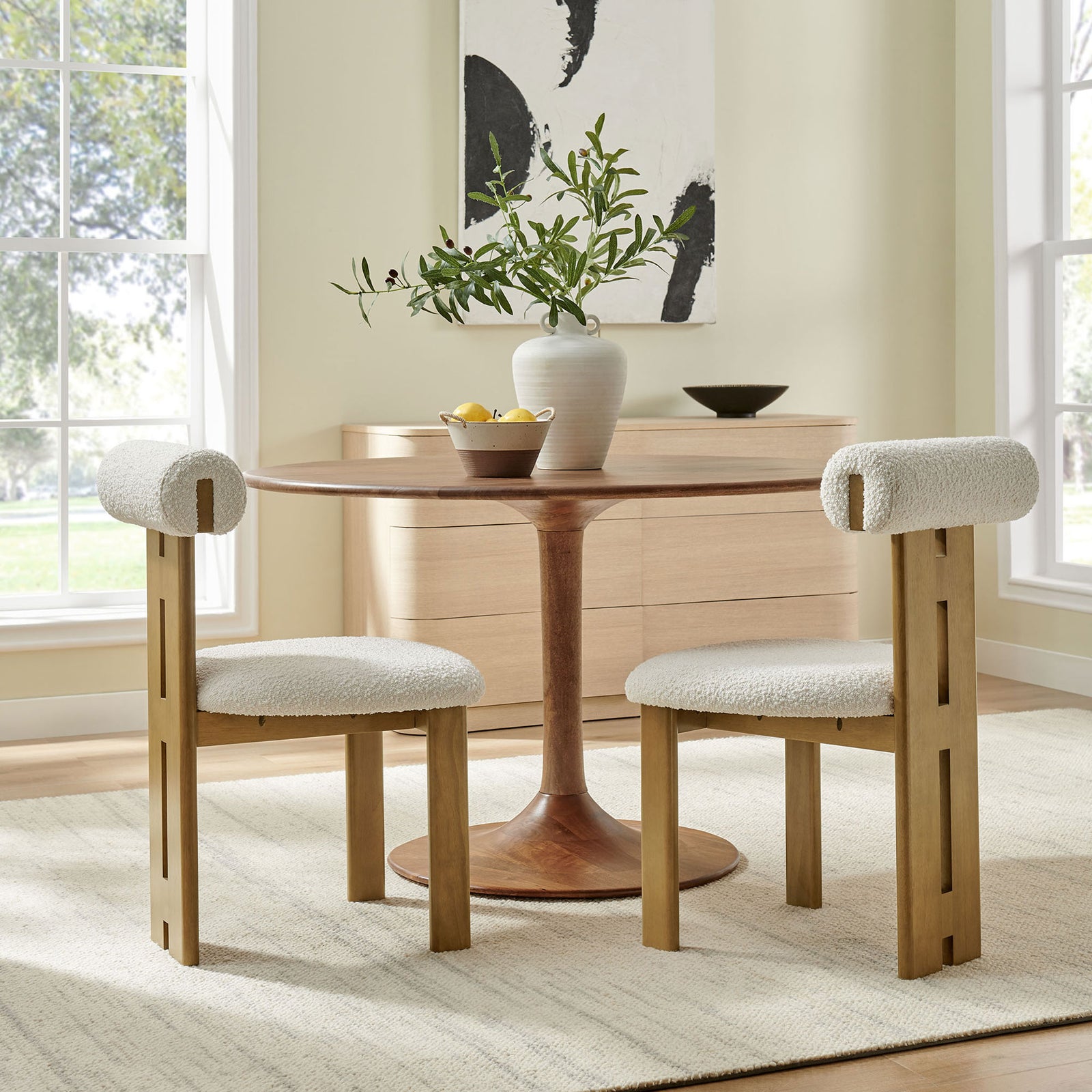Pair of Torian boucle dining chairs surrounding a round pedestal table in a bright airy dining room || EEI-6960-FRO-IVO || side_multi_room