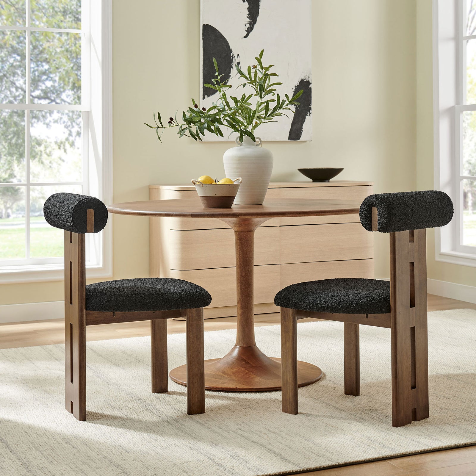 Two walnut and black boucle dining chairs paired with a round pedestal table in a light filled room || EEI-6960-WAL-BLK || front_angle_multi_room