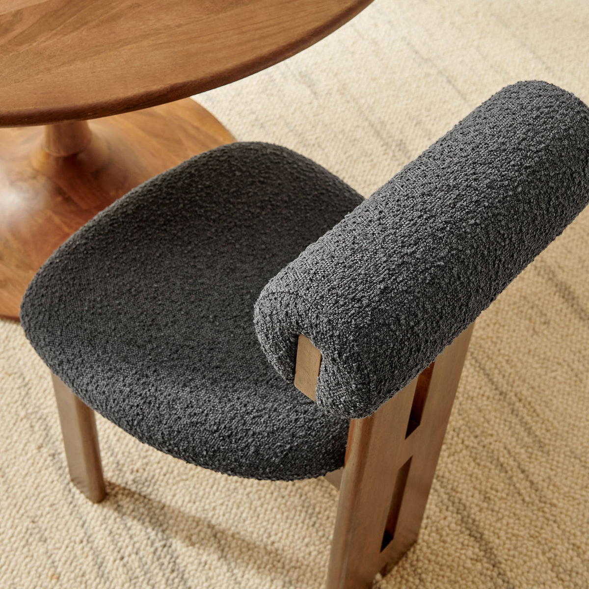 Torian chair styled at a round wood table highlights cozy charcoal boucle seat and modern sculptural lines || EEI-6960-WAL-CHA || detail_room