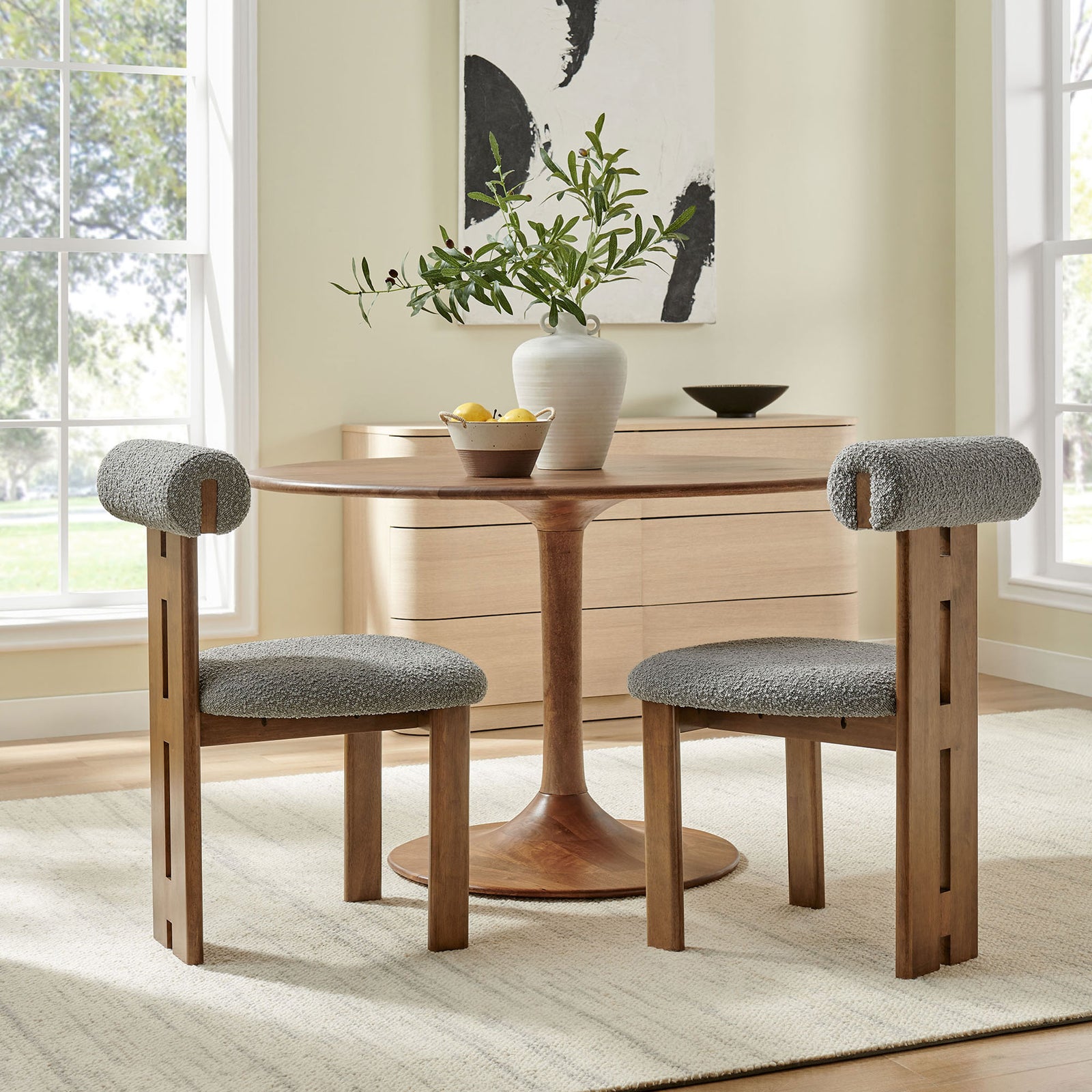 Two walnut dining chairs with gray boucle cushions around a round pedestal table in airy dining room || EEI-6960-WAL-LGR || side_multi_room