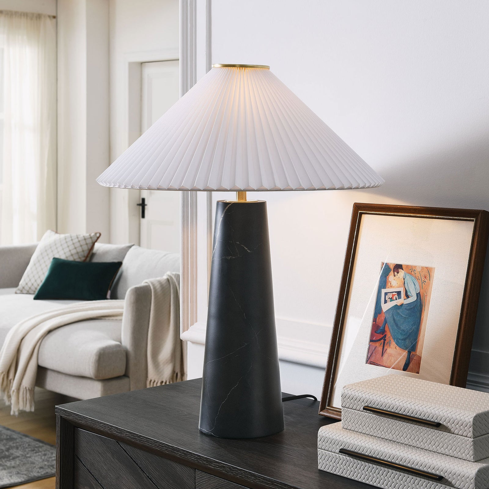 Black marble Nera table lamp glowing warmly on a console table beside art and decor. || EEI-6963-BLK || front_on_room