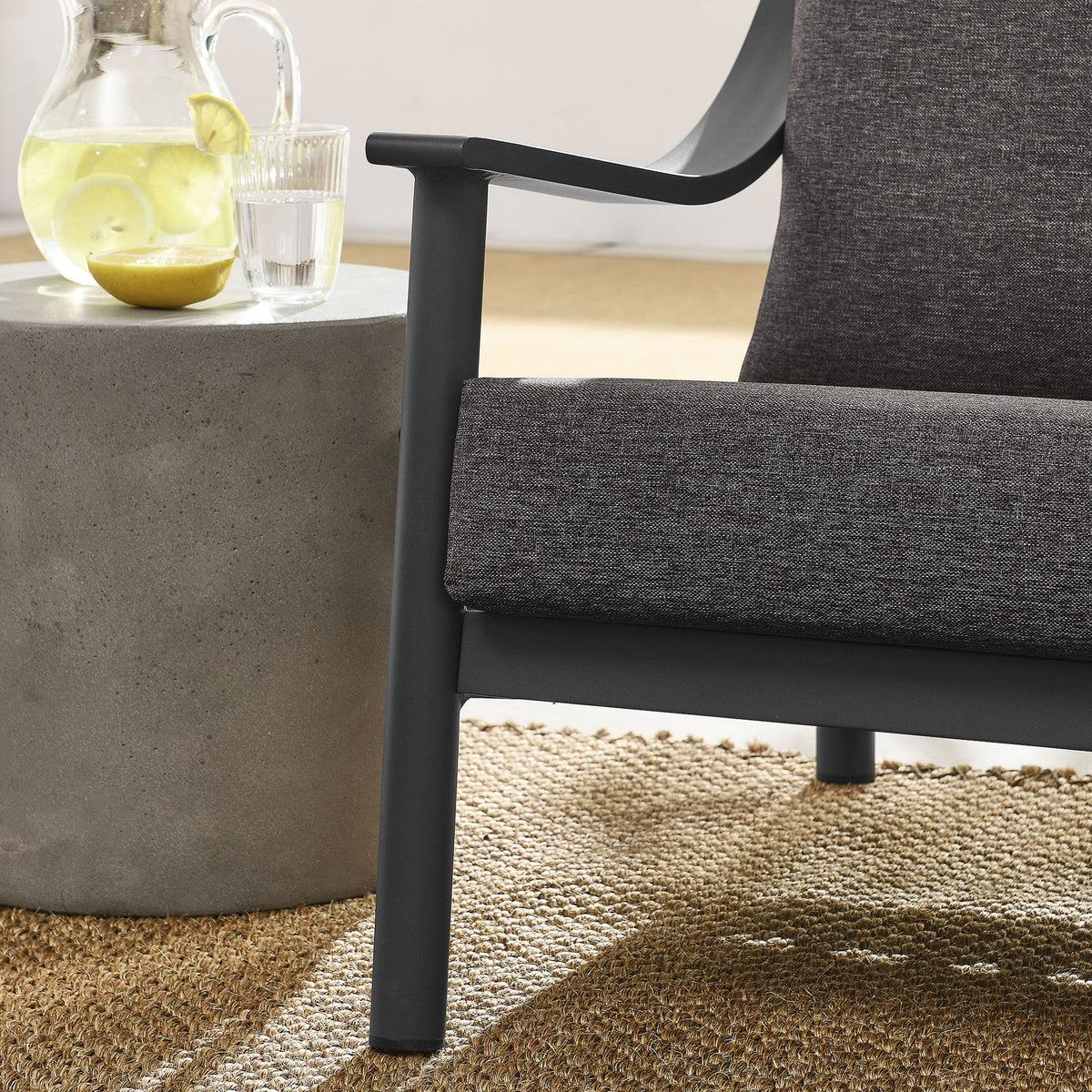 Graphite cushion and dark frame pair with a concrete side table for a modern outdoor lounge vignette || EEI-6976-CAR-GPH || detail_room