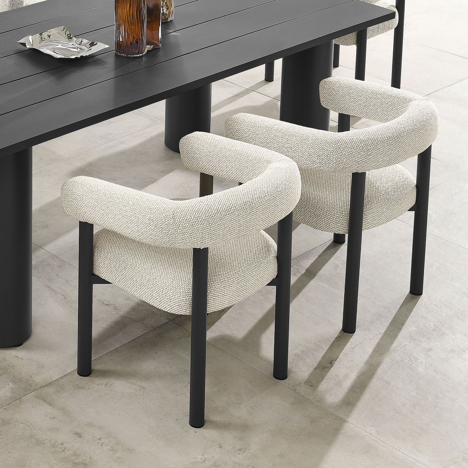 Pair of ivory armchairs flanking a dark outdoor dining table on a clean stone patio || EEI-6979-IVO-GPH || front_angle_multi_room