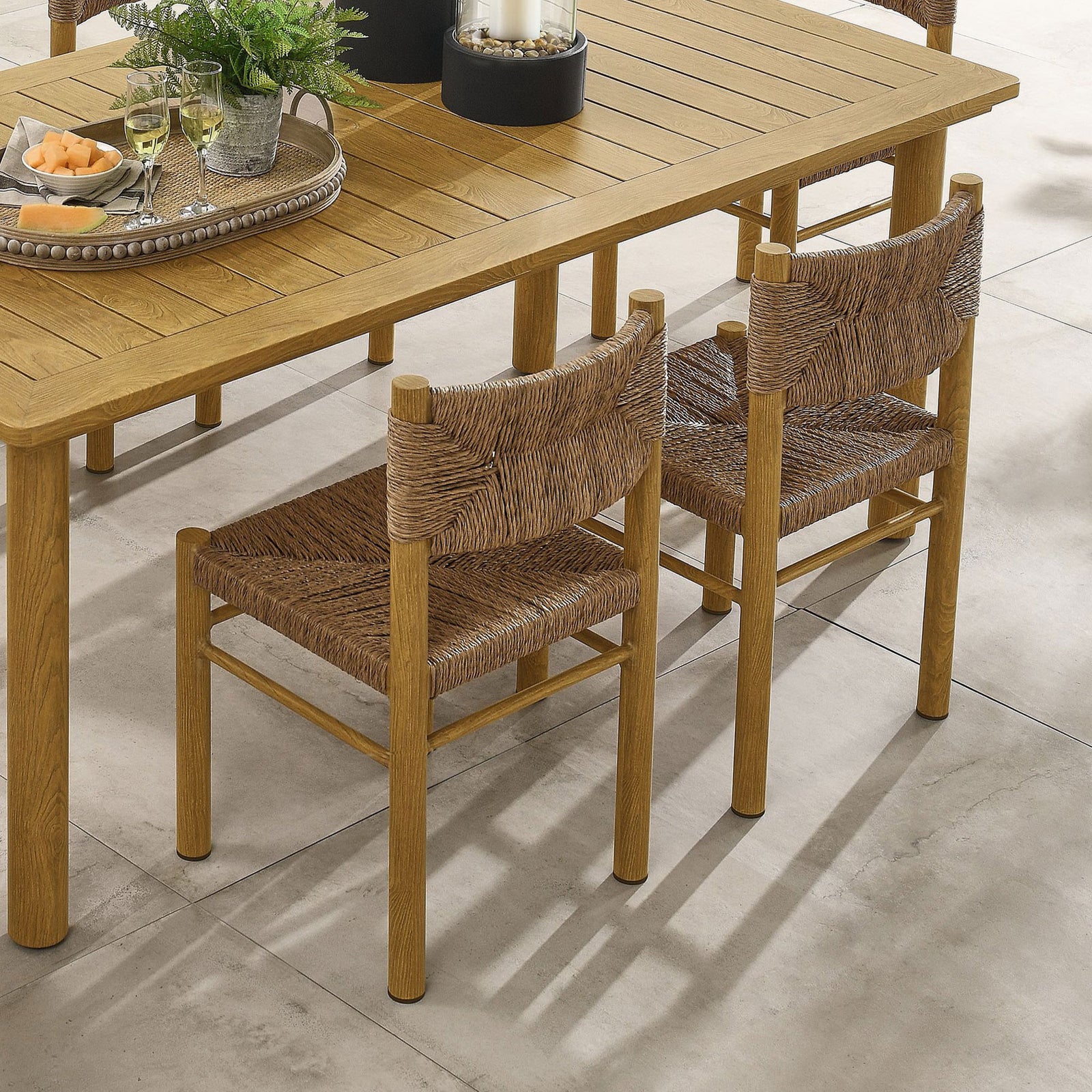 Set of two natural rattan dining chairs paired with a wood grain table for a cohesive outdoor dining area || EEI-6982-NAT || front_angle_multi_room