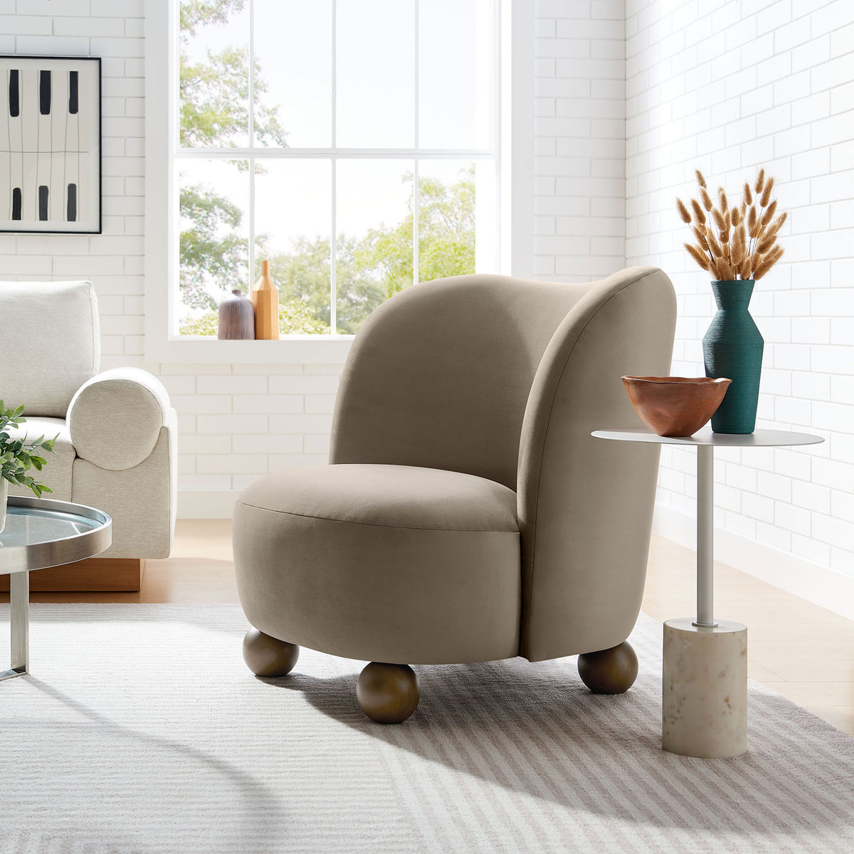 Mid-century taupe velvet chair with rounded feet styled in a bright living room || EEI-6990-TAU-WAL || front_angle_room