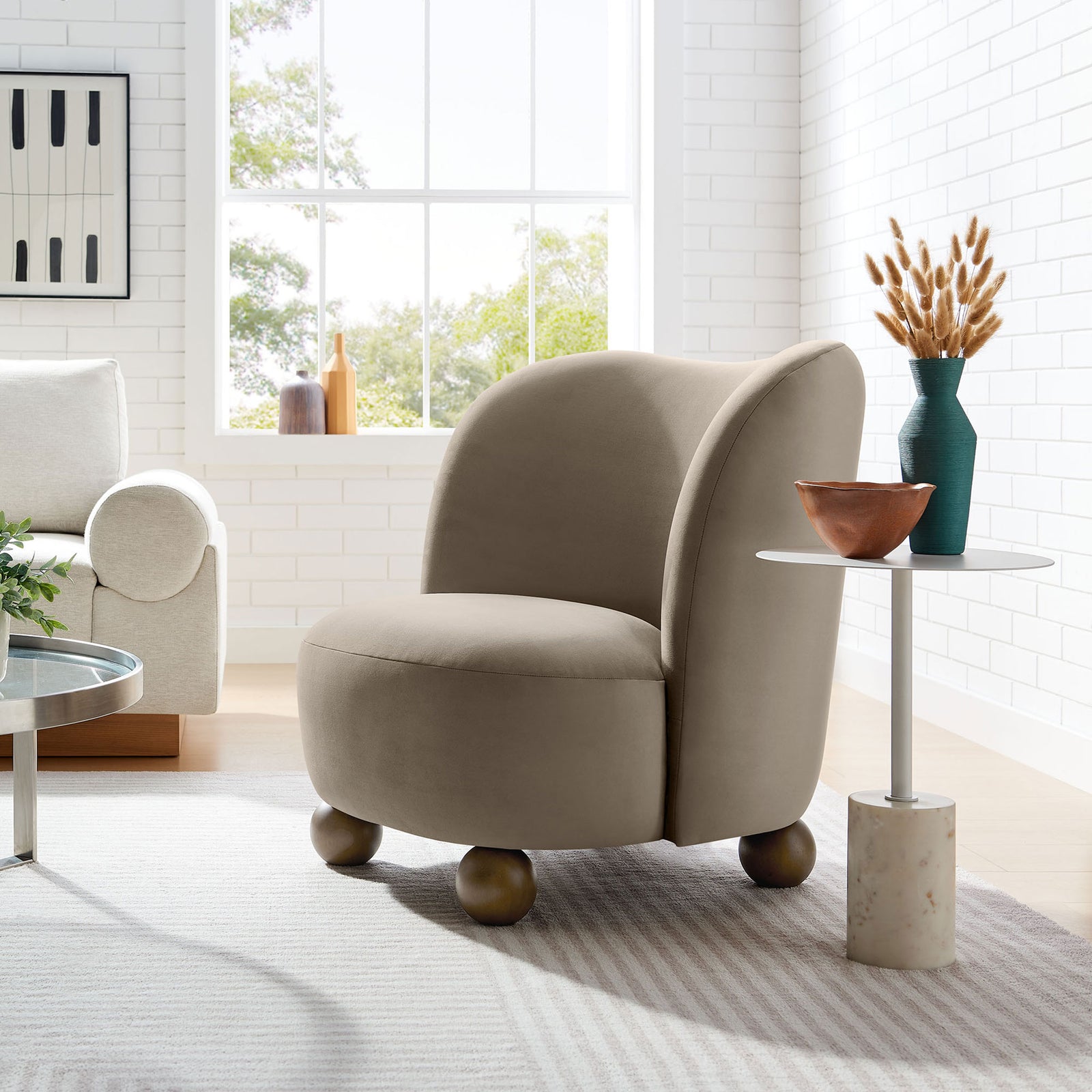 Mid-century taupe velvet chair with rounded feet styled in a bright living room || EEI-6990-TAU-WAL || front_angle_room