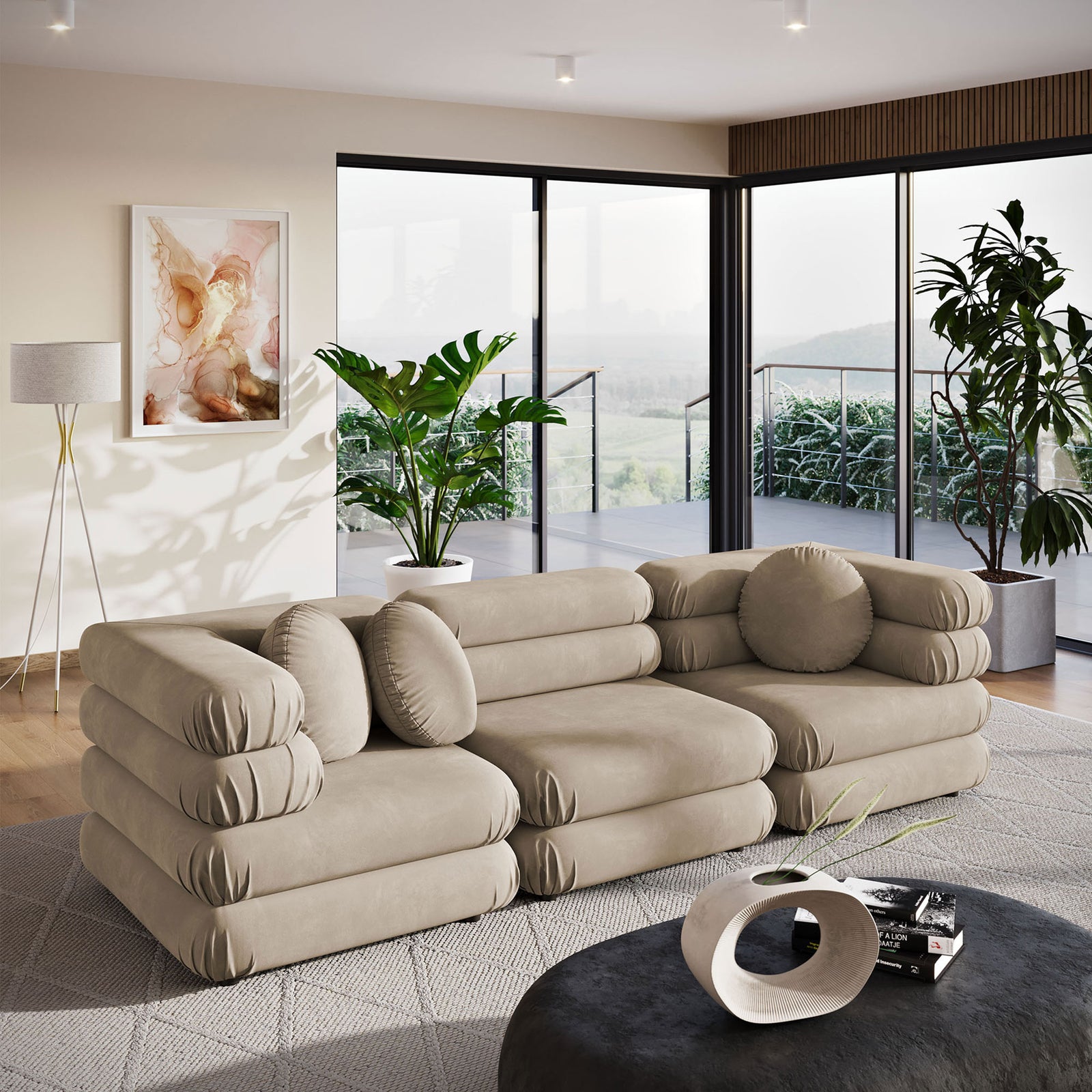 Taupe velvet three piece sectional in modern living room with large windows, greenery, and coordinating round pillows || EEI-7003-TAU || front_angle_room