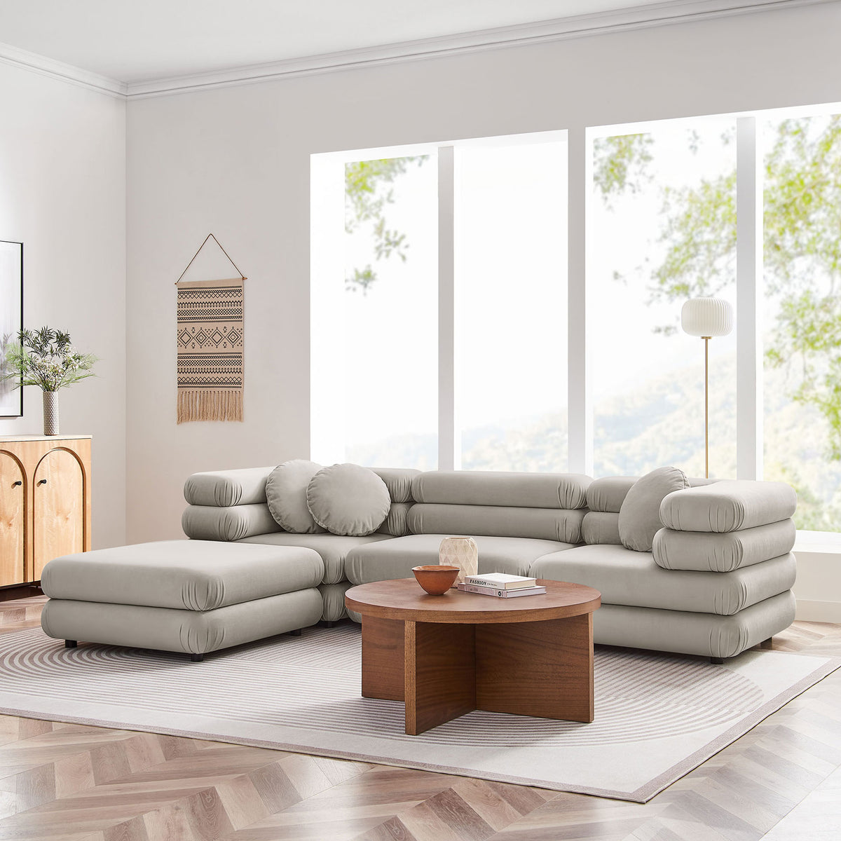 Almond performance velvet modular sectional with ottoman arranged in a bright, airy living room || EEI-7004-ALM || front_angle_room