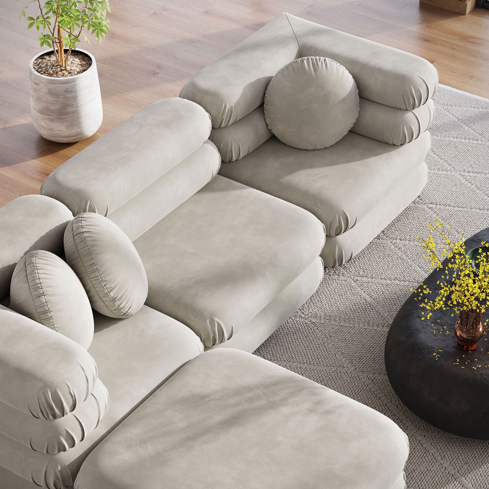 Almond modular sectional and ottoman surrounding a round coffee table, showcasing plush stacked cushions and pillows || EEI-7004-ALM || top_angle_room