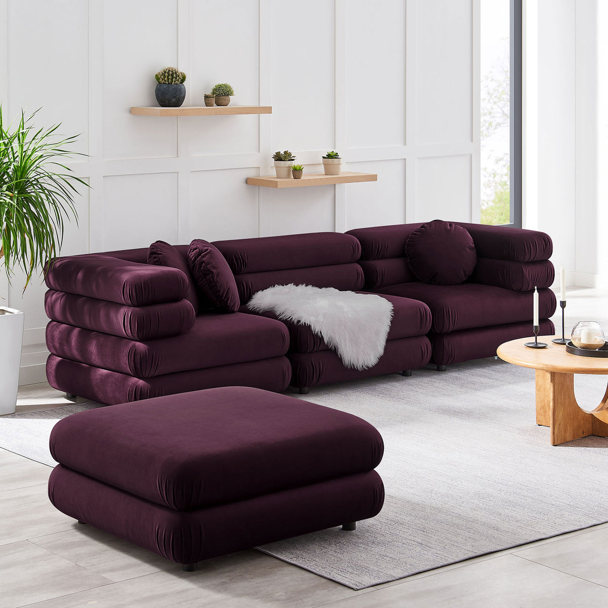 Modular mulberry sectional and matching ottoman create a flexible lounge layout with plush layered cushions || EEI-7004-MUL || front_angle_room