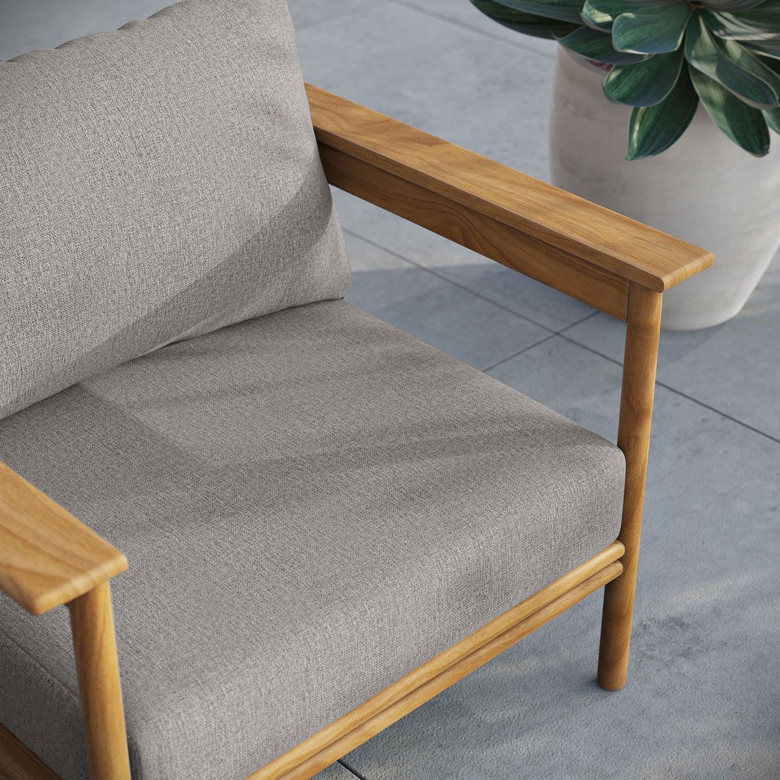 Teak outdoor armchair with light gray cushions styled on a modern patio beside a potted succulent || EEI-7007-NAT-DRI || detail_room