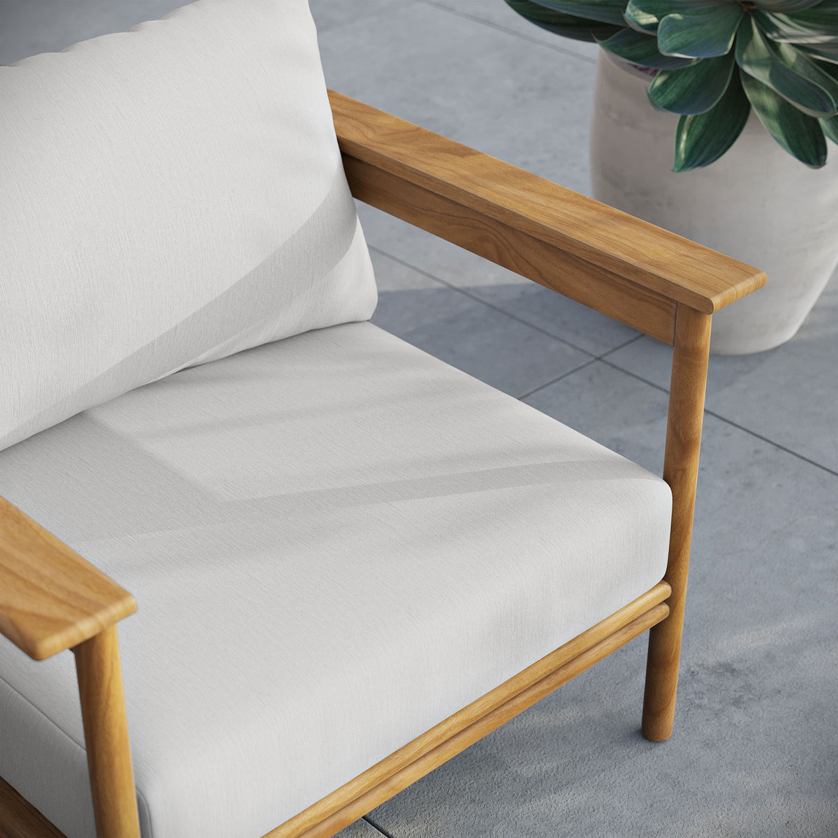 White cushioned teak armchair styled on a modern patio next to a large potted succulent || EEI-7007-NAT-SAI || detail_room