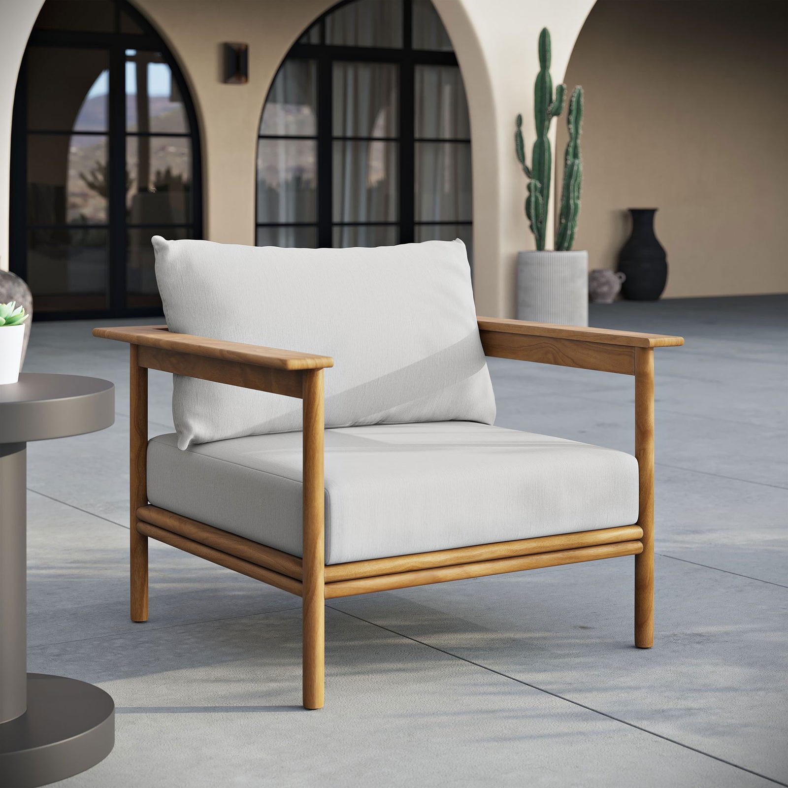White-cushioned teak patio armchair set on a spacious terrace with arched outdoor architecture || EEI-7007-NAT-SAI || front_angle_room
