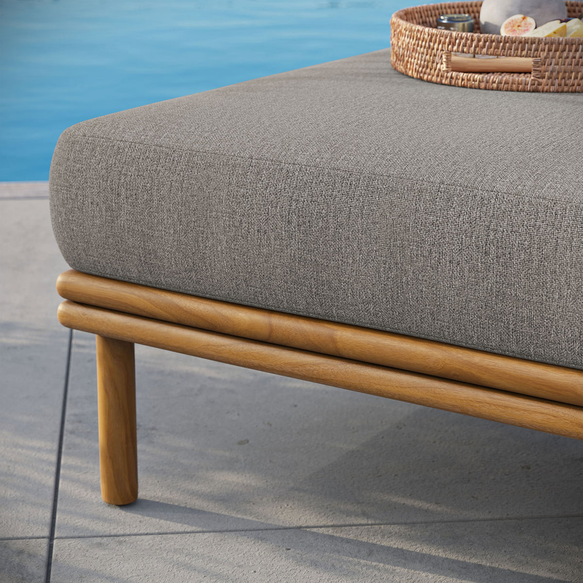 Teak base and soft cushion sit on a sunlit patio, ready to pair with your favorite outdoor seating pieces. || EEI-7009-NAT-DRI || detail_room