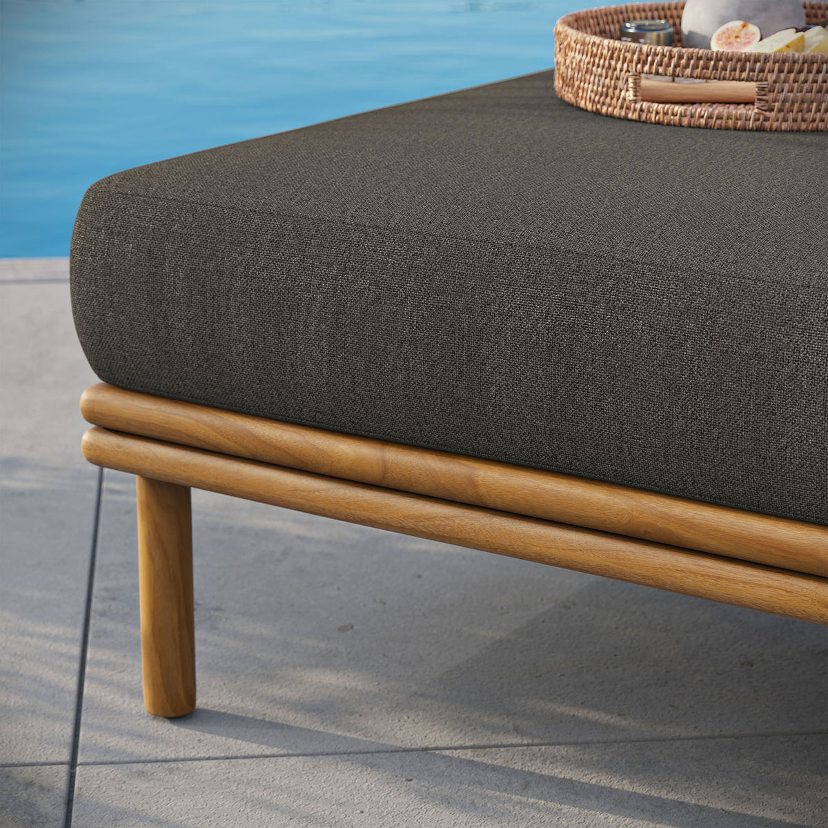 Dark cushion and warm teak base rest beside the pool, ready to mix with matching outdoor seating. || EEI-7009-NAT-FLI || detail_room