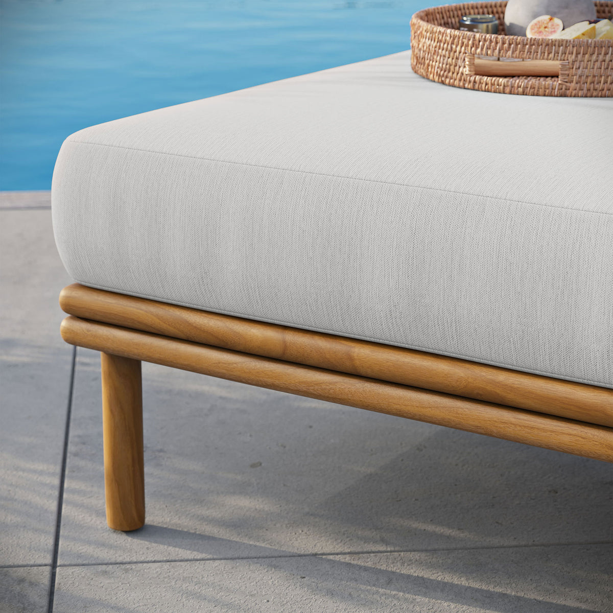 Teak ottoman with crisp white cushion rests on a sunwashed patio beside coordinating outdoor seating. || EEI-7009-NAT-SAI || detail_room