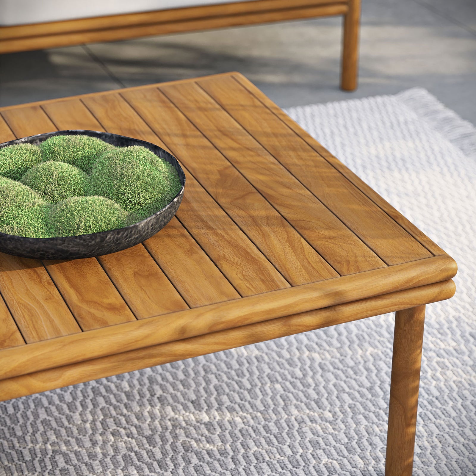 Teak coffee table corner styled on outdoor rug with decorative bowl of greenery on the slatted top || EEI-7010-NAT || detail_room