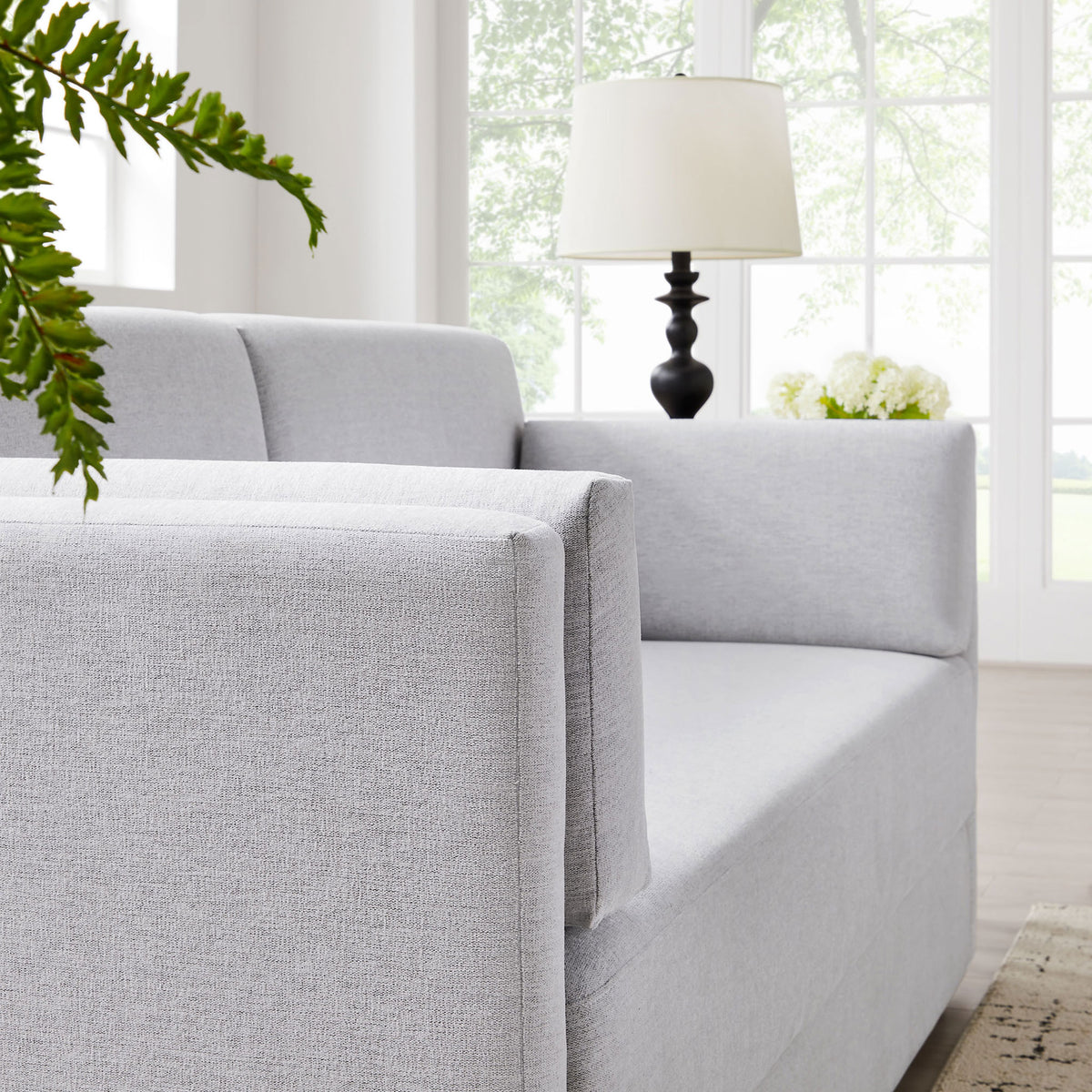 Light gray sofa frames a cozy corner with layered cushions and soft natural light || EEI-7012-NPT || detail_room