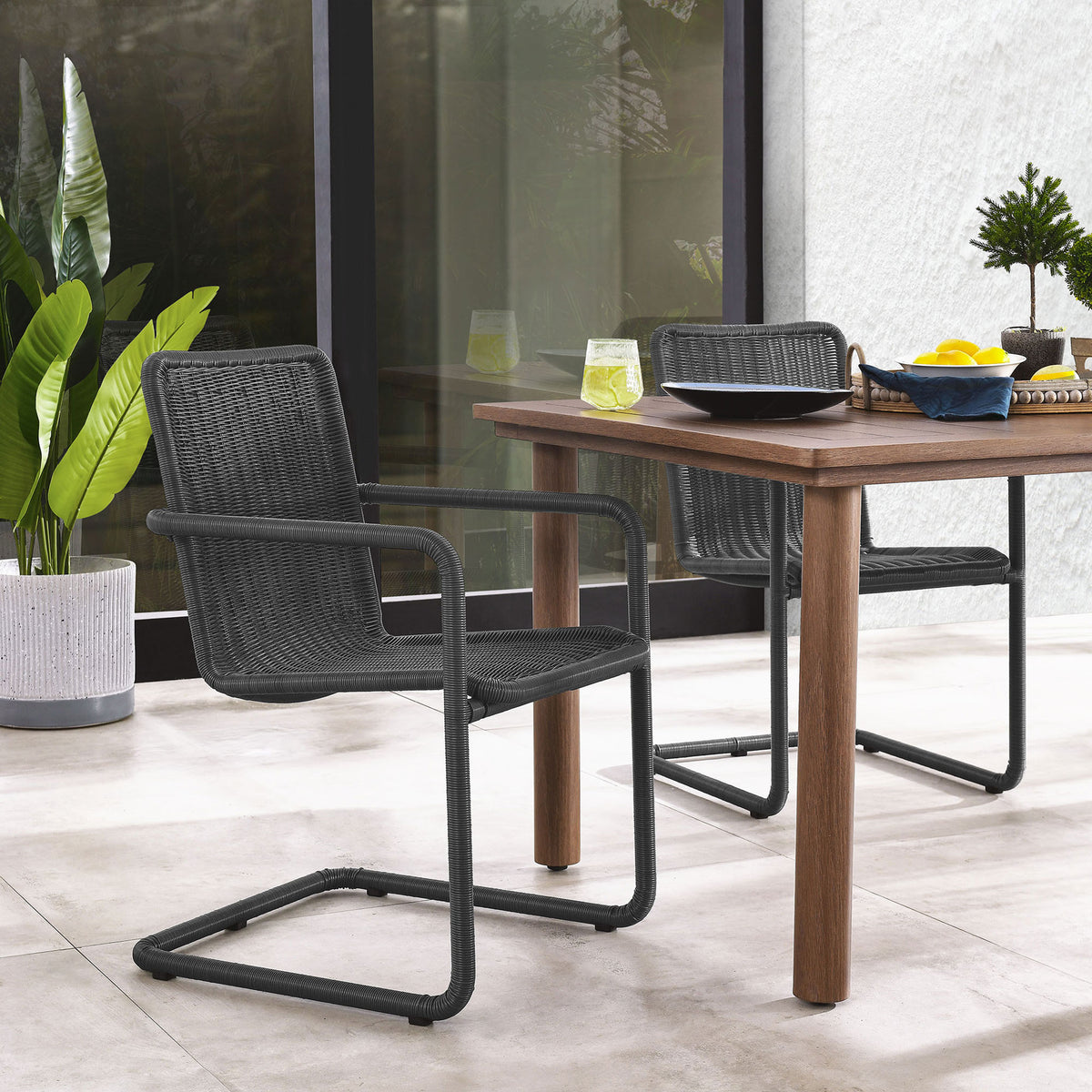 Slate wicker chairs arranged around a wood dining table on a bright modern patio || EEI-7014-SLA || front_angle_multi_room