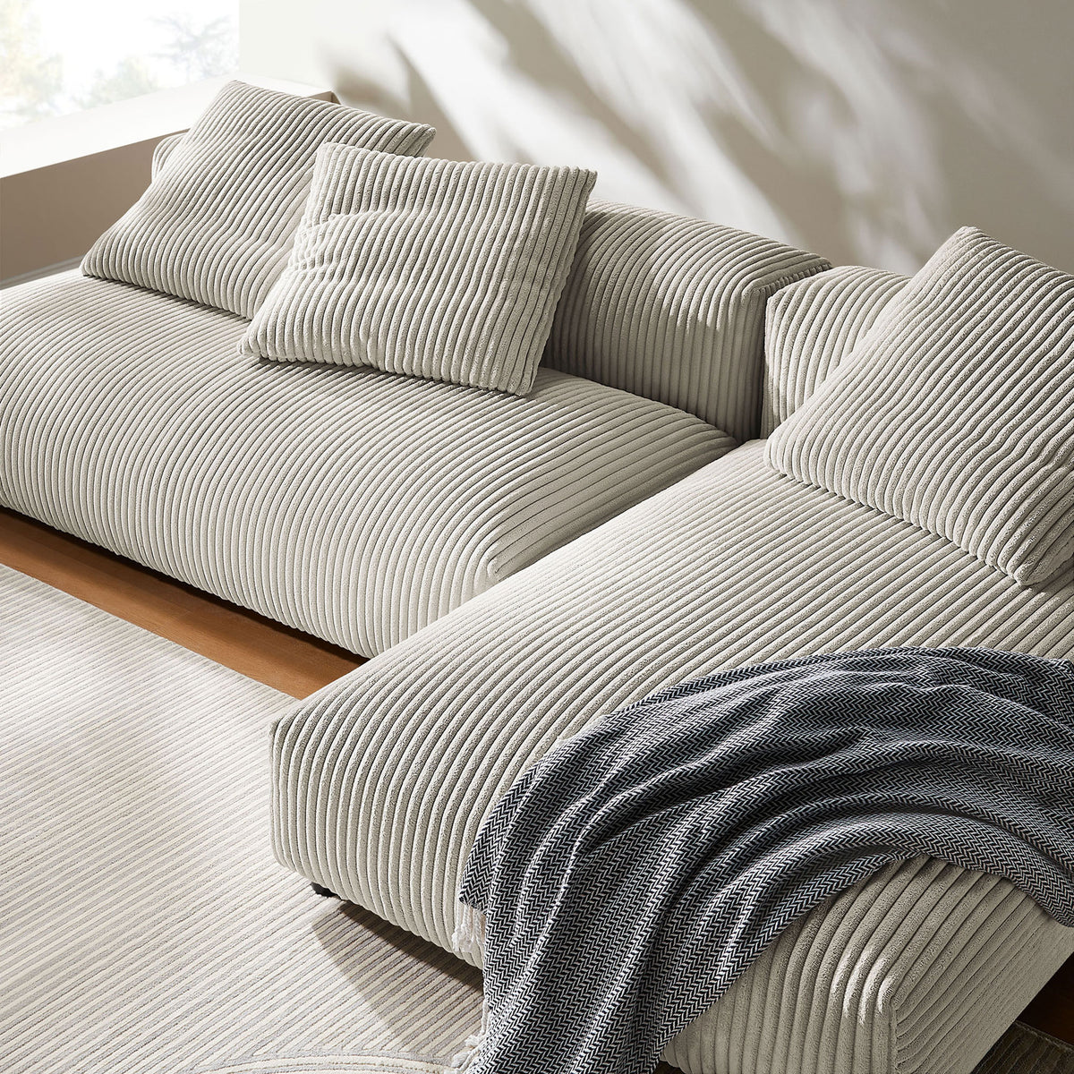 Textured almond corduroy chaise sectional styled with pillows and a soft throw for a cozy look || EEI-7024-ALM || detail_room