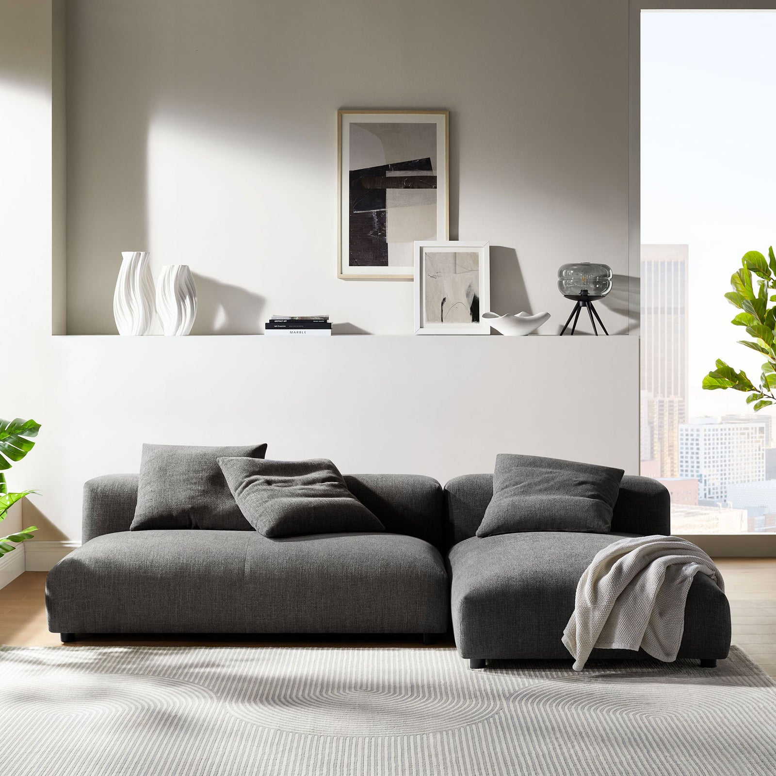 Charcoal modular sectional with chaise anchored in a bright living room with airy, modern decor. || EEI-7025-CHA || front_room