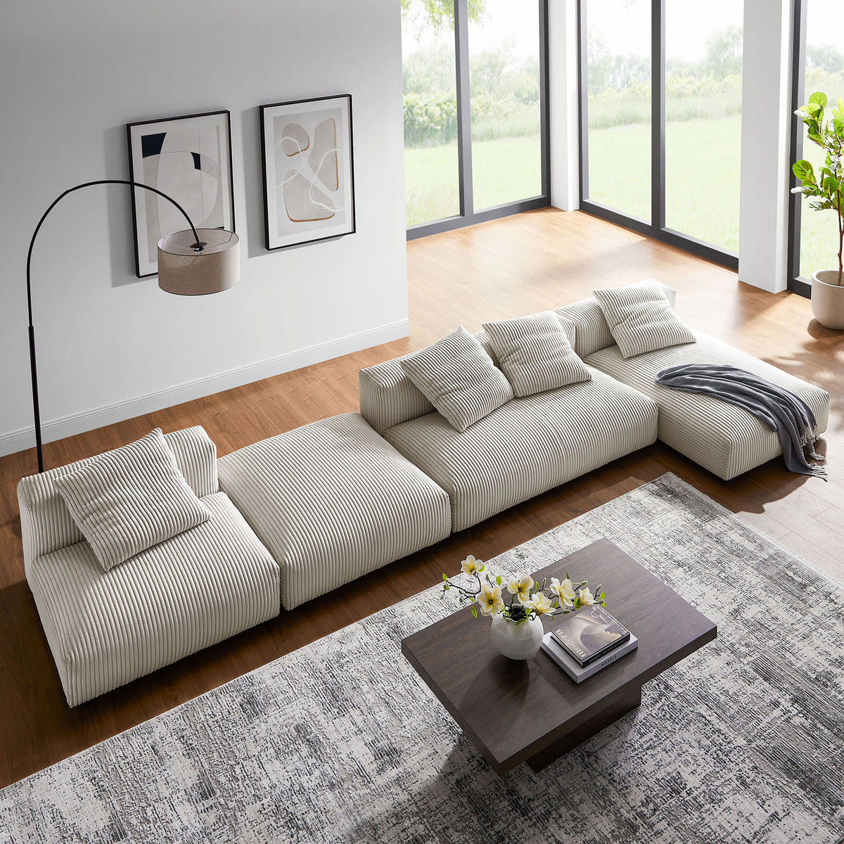 Modular almond corduroy sectional arranged as a long sofa with throw blanket in an airy, windowed room || EEI-7032-ALM || top_angle_partial_room