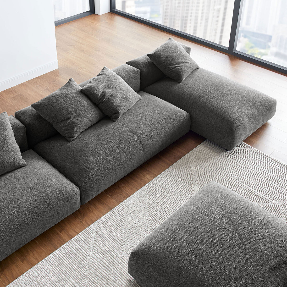 Charcoal modular sectional with ottoman styled in a bright modern living room with floor to ceiling windows || EEI-7033-CHA || detail_room