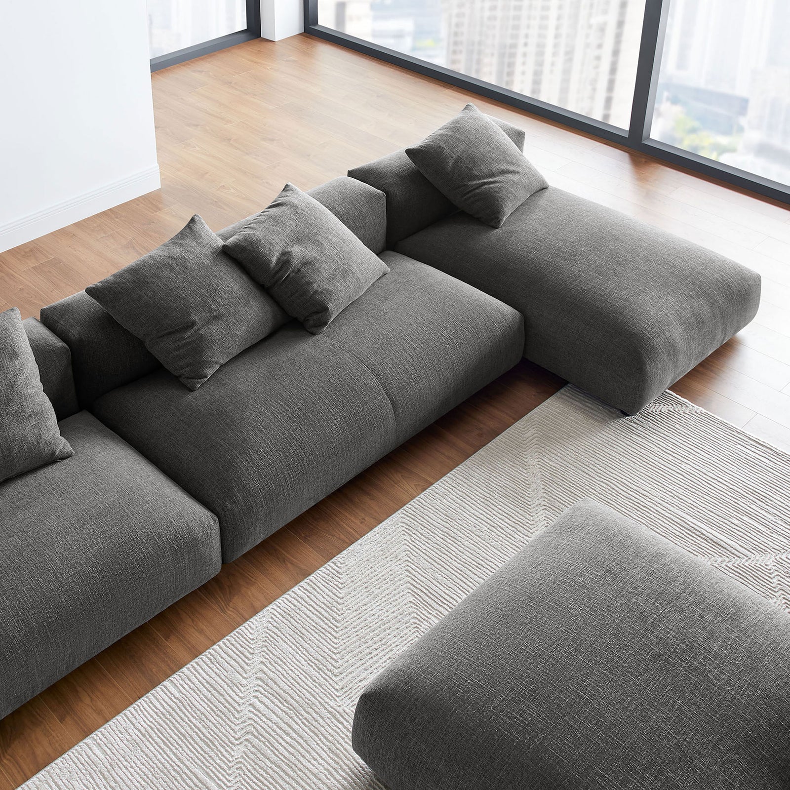 Charcoal modular sectional with ottoman styled in a bright modern living room with floor to ceiling windows || EEI-7033-CHA || detail_room