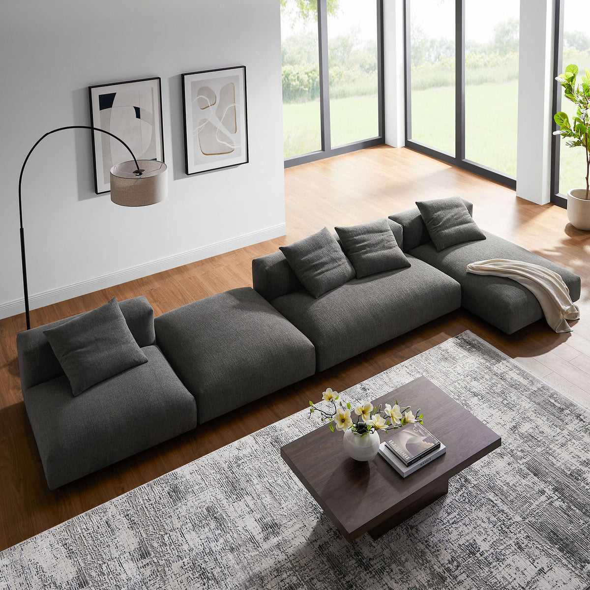 Low profile charcoal modular sectional arranged flush to the floor beside a wood coffee table and decor || EEI-7033-CHA || top_angle_room