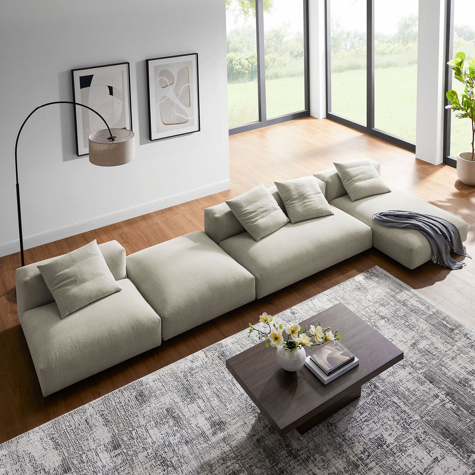 Extended linen modular sectional sofa with ottoman beside a wood coffee table and large windows || EEI-7033-LIN || top_angle_room