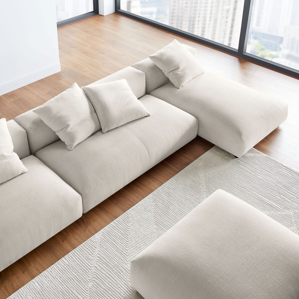 Modular salt fabric sectional with ottoman arranged in an airy living space with expansive floor to ceiling windows || EEI-7033-SAL || detail_room
