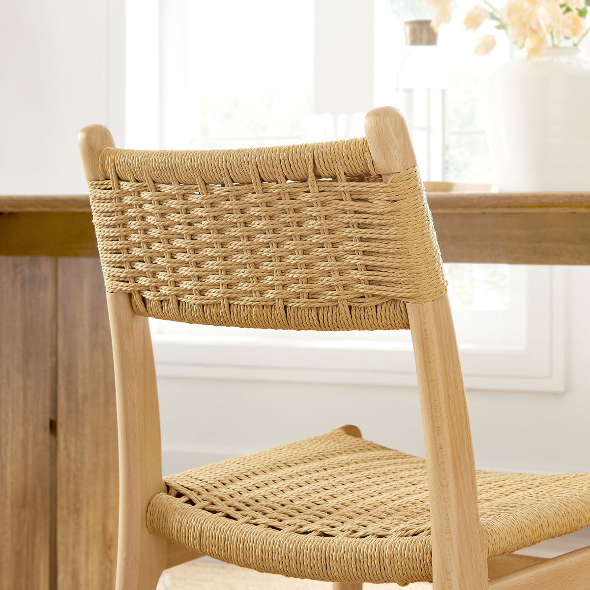 Natural rope backrest and light wood frame add relaxed, organic texture to a bright dining space. || EEI-7044-NAT-NAT || detail_room