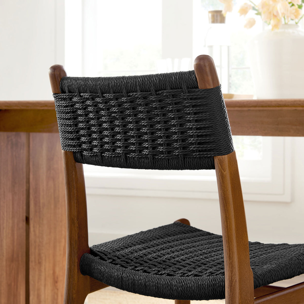 Black woven rope backrest framed by rich walnut wood adding natural texture to a bright dining space || EEI-7044-WAL-BLK || detail_room