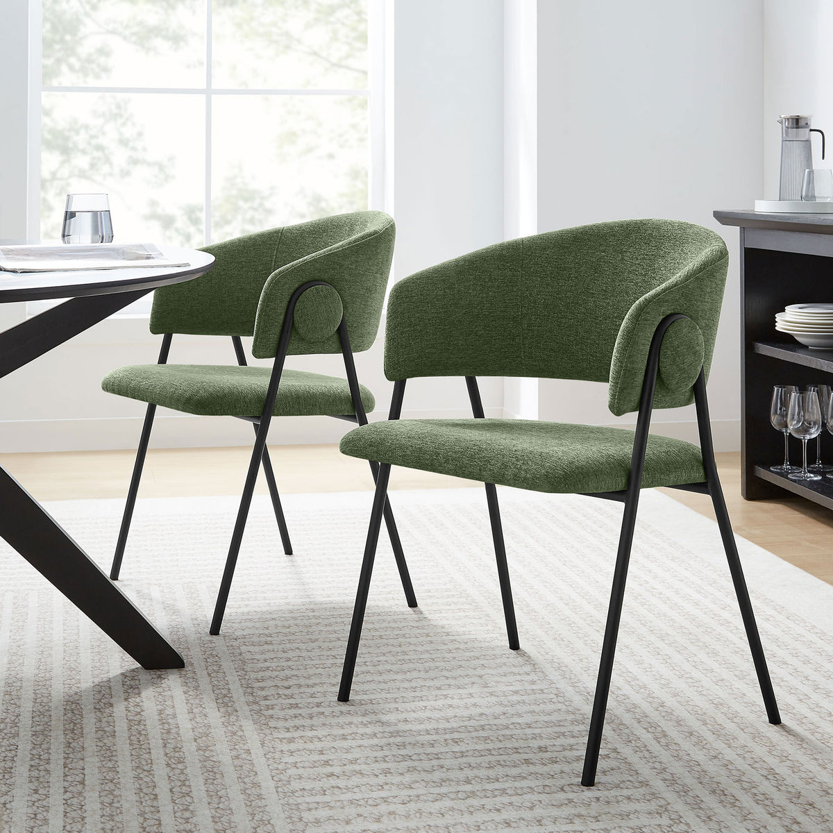 Set of two green chenille dining chairs with barrel backs styled around a modern dining table in a bright room || EEI-7045-EUC-BLK || front_angle_multi_room