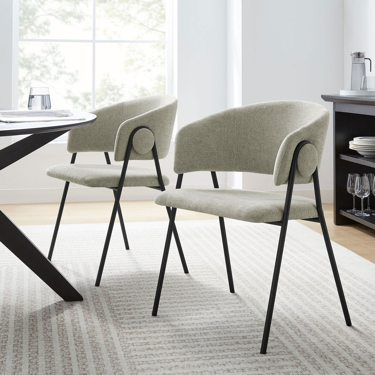 Pair of taupe chenille dining chairs around a modern table in a light filled dining space. || EEI-7045-TAU-BLK || front_angle_multi_room