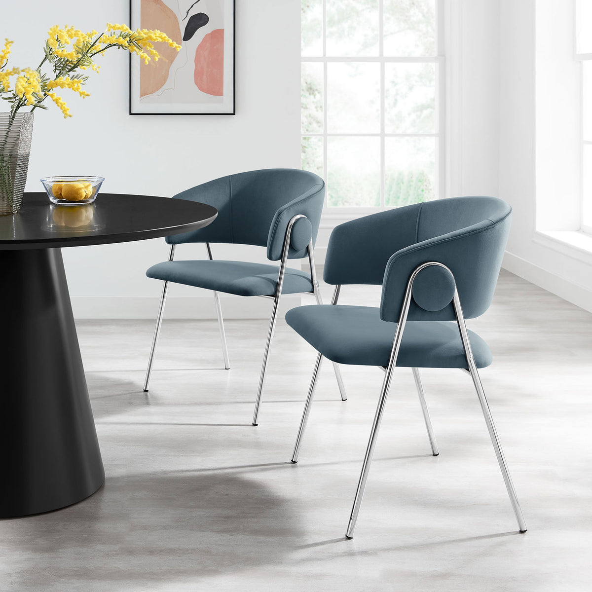 Two cadet blue velvet dining chairs styled around a contemporary table in a bright dining room. || EEI-7046-CAD-SLV || front_angle_multi_room