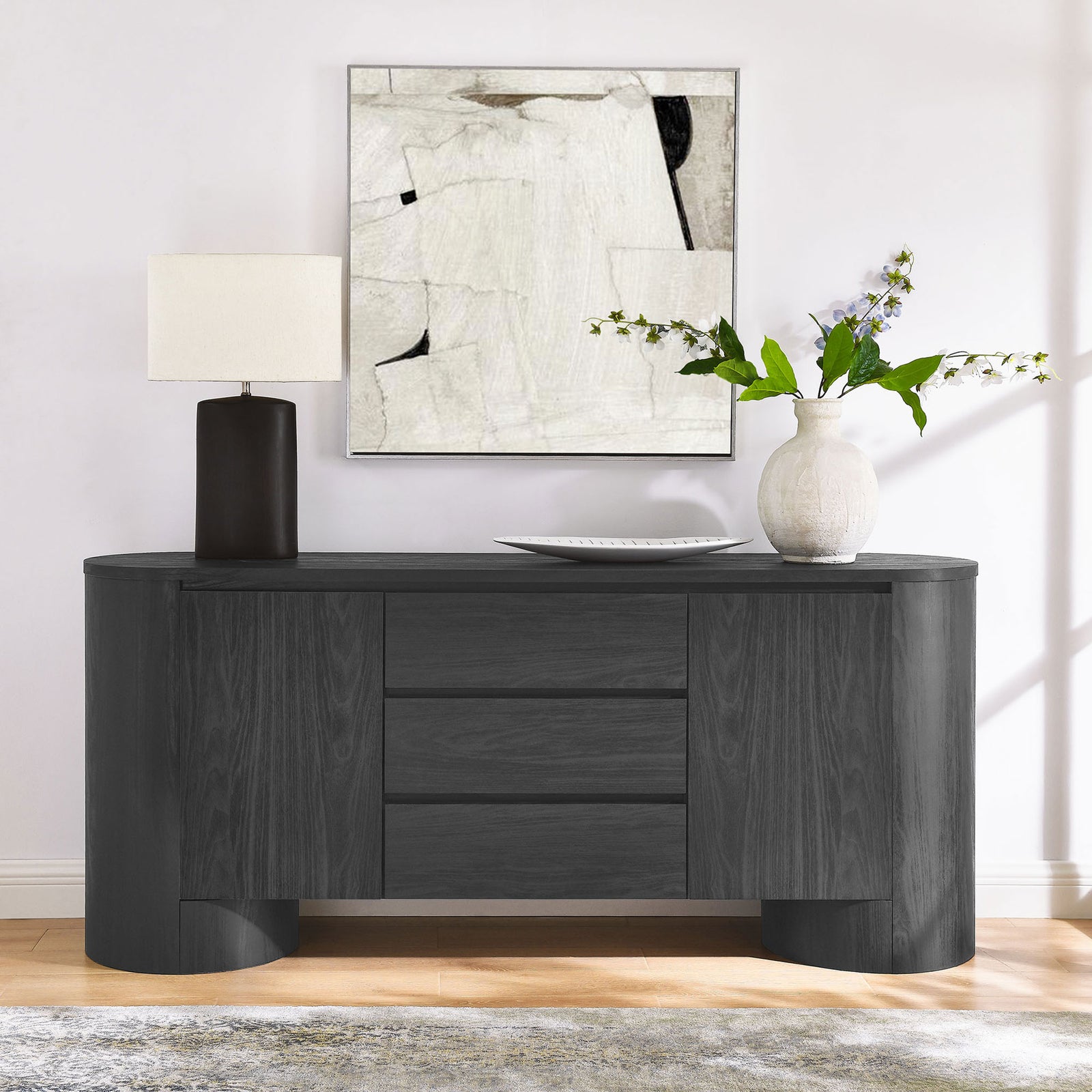 Oval black sideboard serves as an elegant console table with layered decor in a contemporary living space || EEI-7050-BLK || front_angle_room