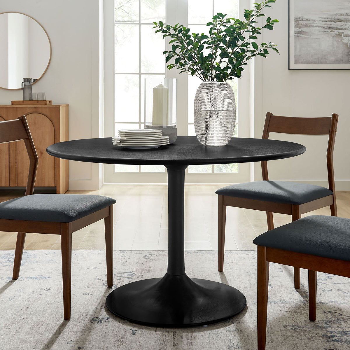 Black round pedestal dining table surrounded by chairs in a bright mid century inspired dining room || EEI-7051-BLK || front_angle_room