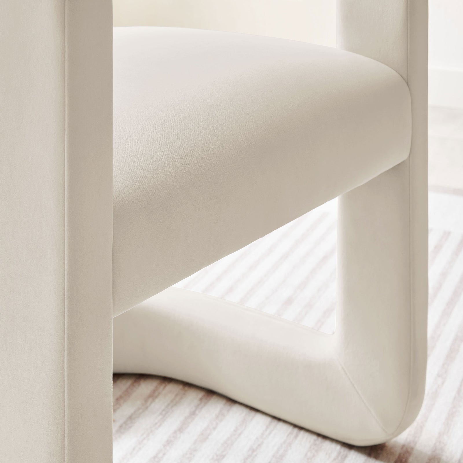 Alabaster velvet chair base and seat resting on a striped rug, showcasing its plush comfort. || EEI-7052-ALA || detail_room
