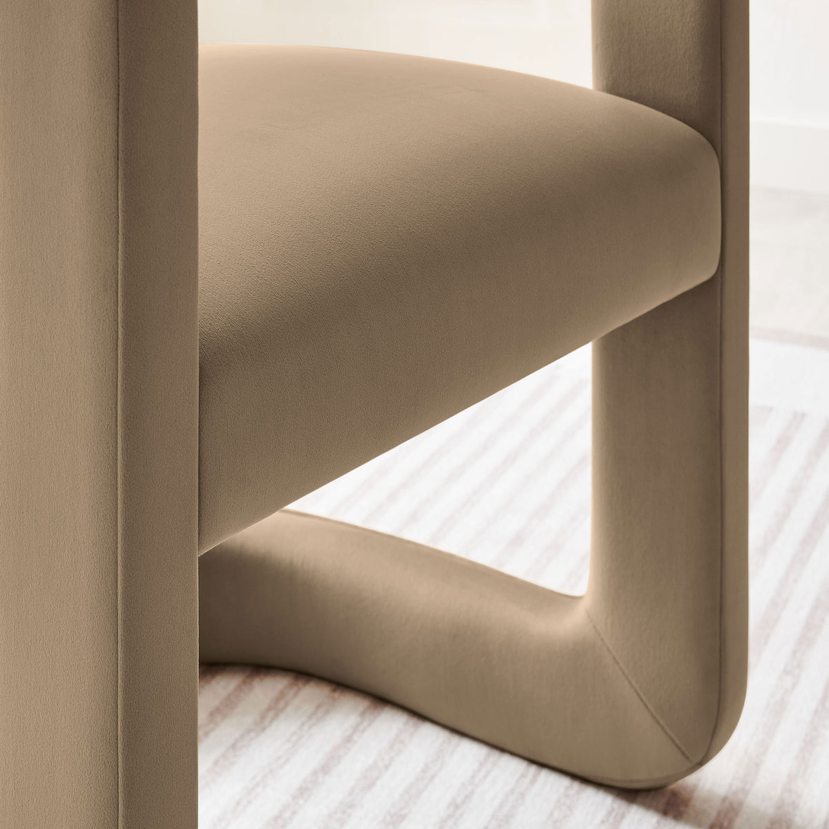 Detail of taupe velvet dining chair seat and base styled over a striped area rug. || EEI-7052-TAU || detail_room