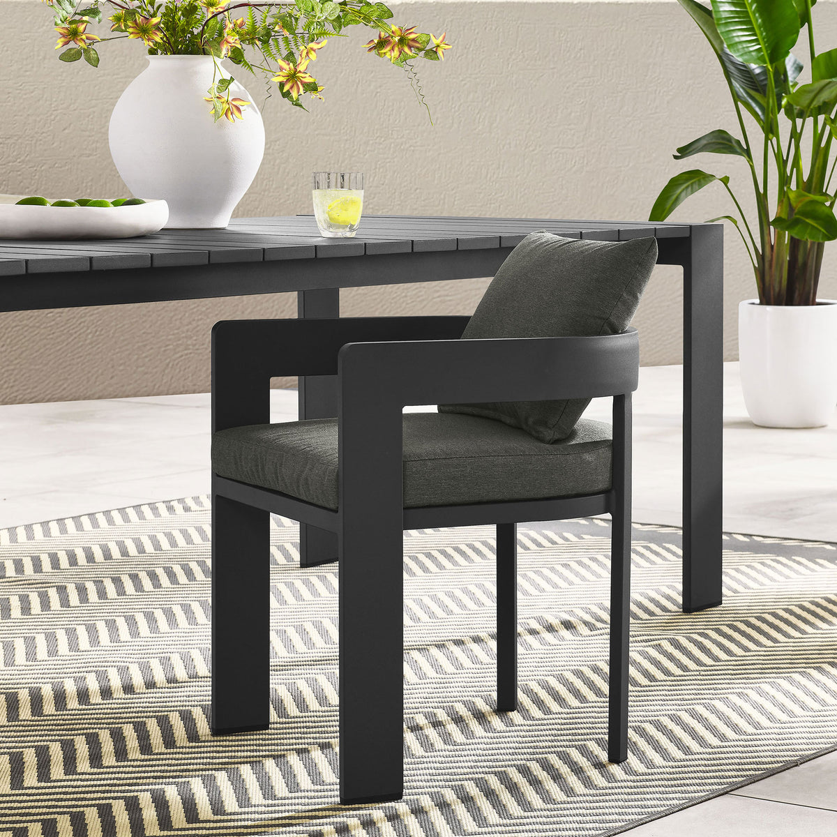 Charcoal Tahoe patio dining chair with dark gray cushions styled at a modern outdoor dining table || EEI-7053-GRY-CHA || front_angle_room