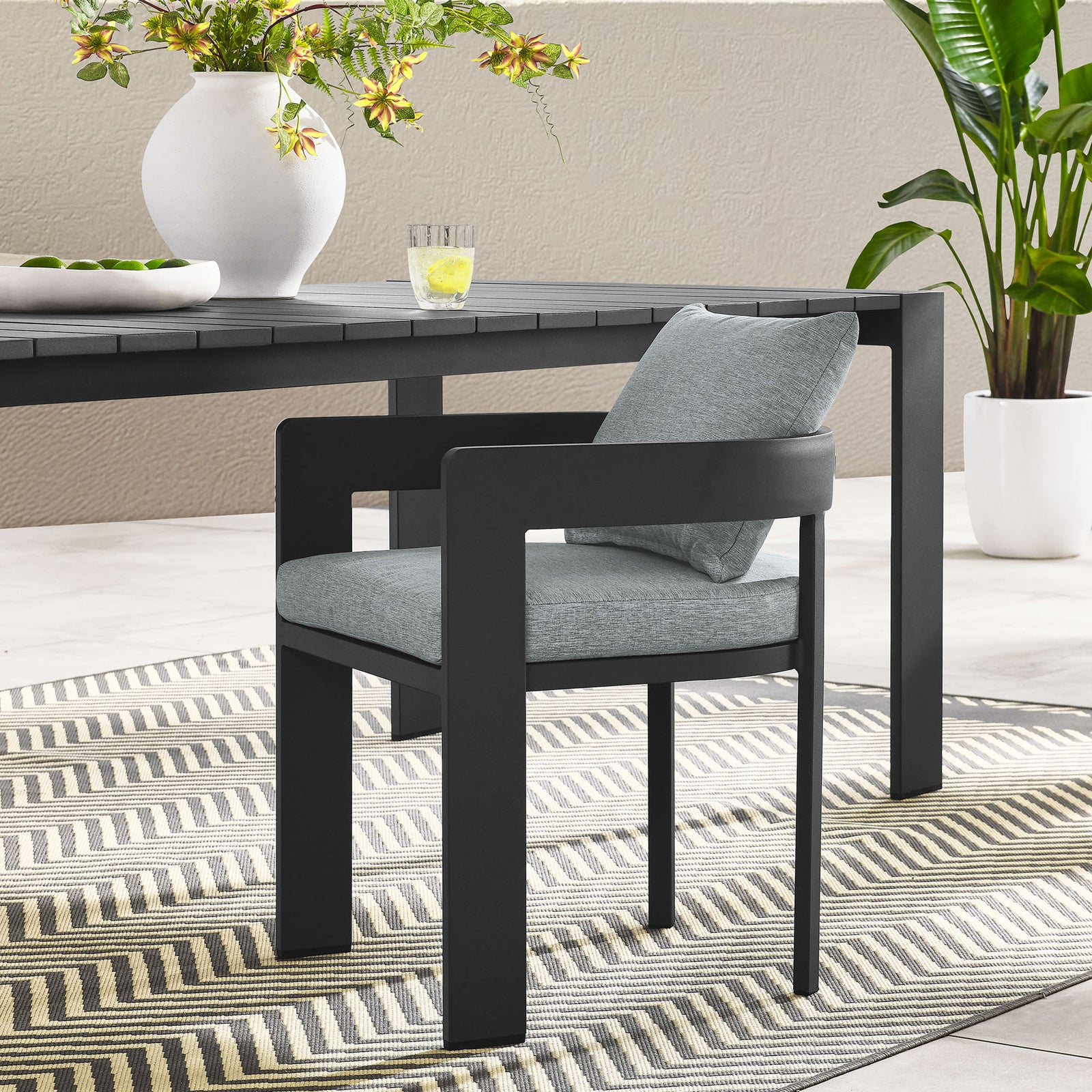 Charcoal Tahoe patio dining chair with light gray cushions styled around a modern outdoor dining table || EEI-7053-GRY-GRY || front_angle_room