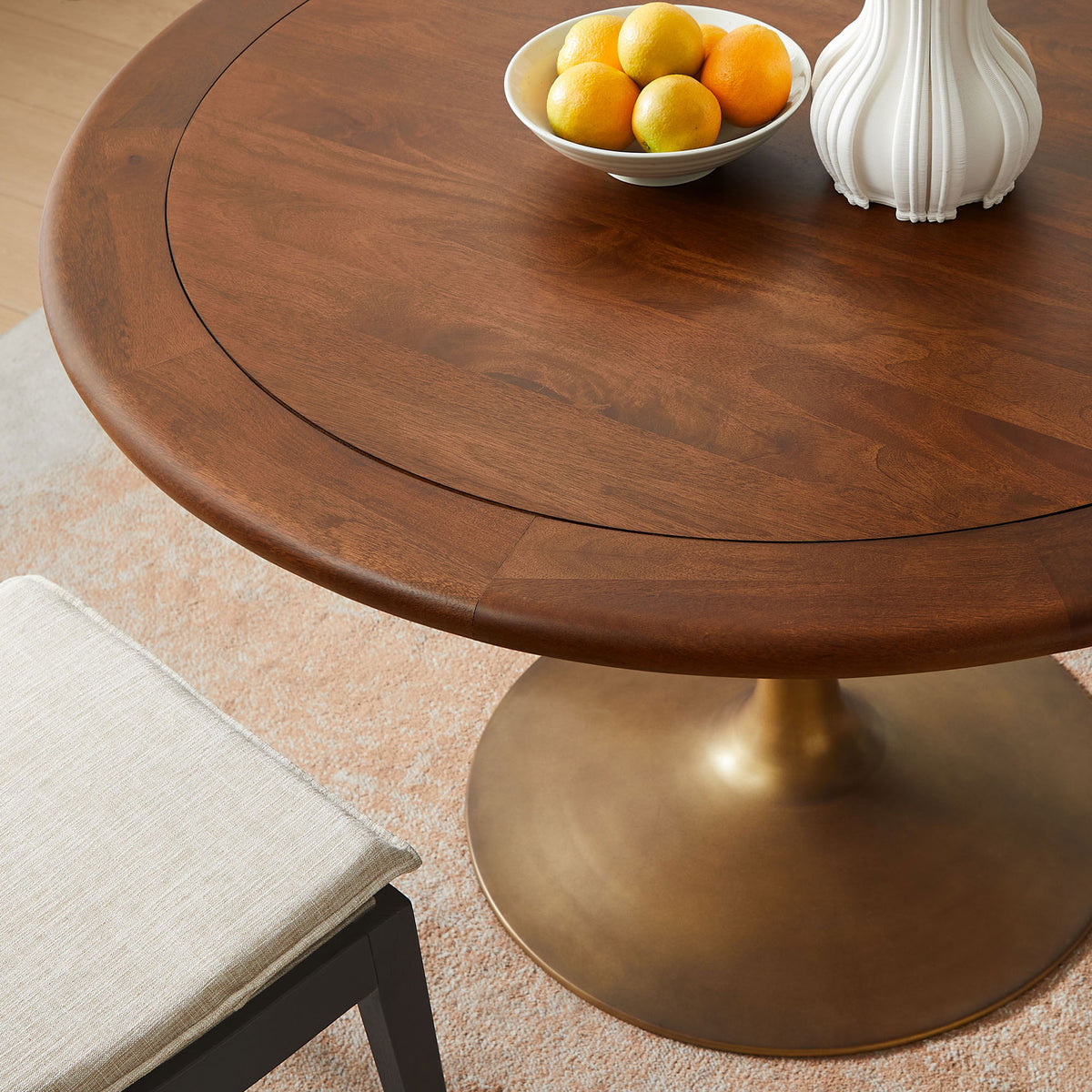 Walnut dining tabletop styled with fruit and decor, highlighting the warm wood tone and brass pedestal base || EEI-7070-BRA-WAL || detail_room