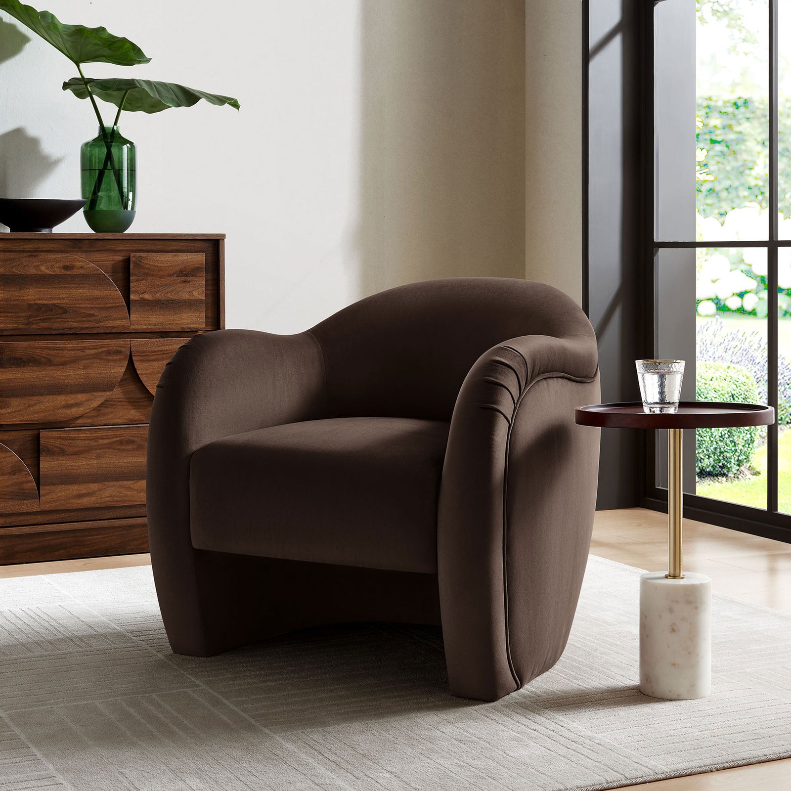 Styled in a modern living space with rich wood tones to showcase the chair's curves. || EEI-7074-CHB || front_angle_room