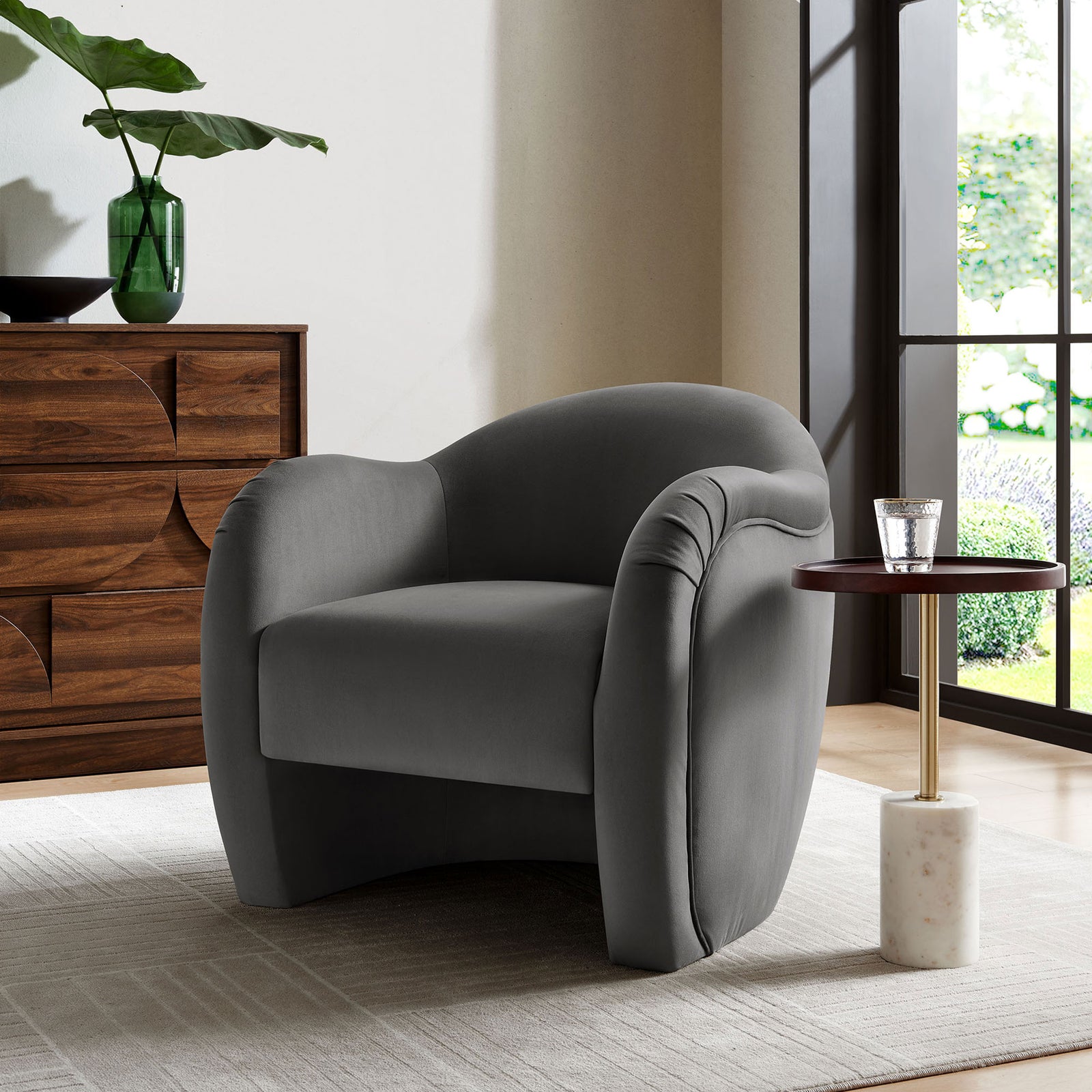 Modern accent chair brings soft curves and storm gray velvet warmth to a bright living space || EEI-7074-STG || front_angle_room