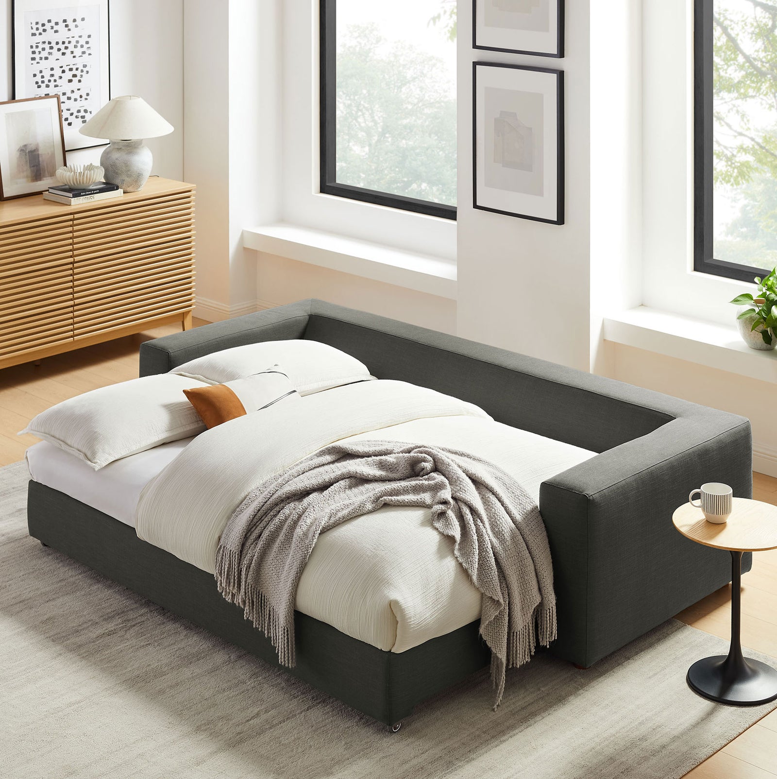 Sleeper sofa transformed into a neatly dressed bed for overnight guests in a modern living room || EEI-7080-GRY || front_angle_converted_room