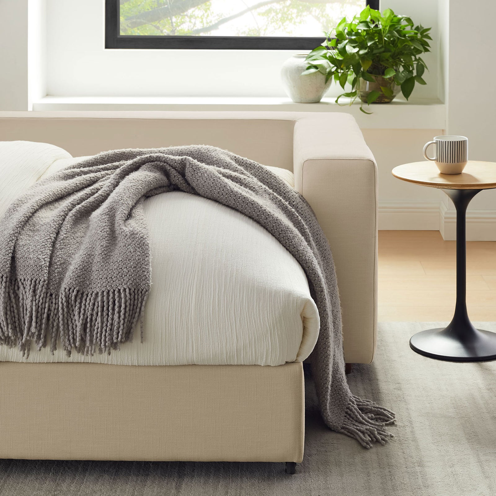 Cozy corner of the sleeper sofa dressed in white bedding with a textured throw and side table || EEI-7080-LBG || detail_room