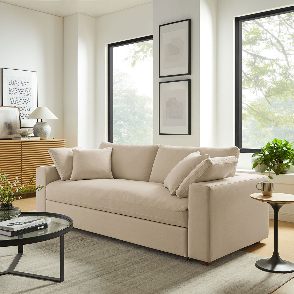 Light beige sleeper sofa anchoring a bright contemporary living room with large windows and layered textures || EEI-7080-LBG || front_angle_room